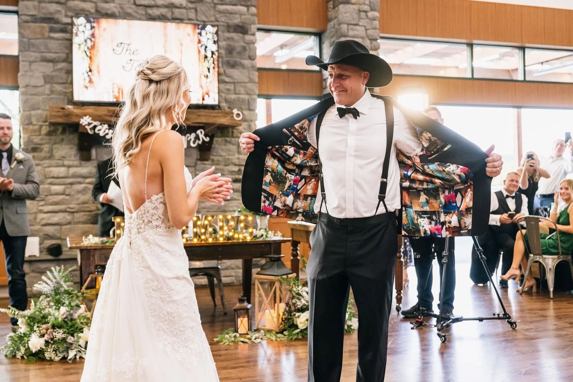 At his reception, a groom in a cowboy hat and tuxedo opens his jacket to show his bride its custom photo lining