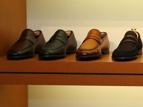 A row of Magnanni penny loafers in brown, green, cognac and black suede