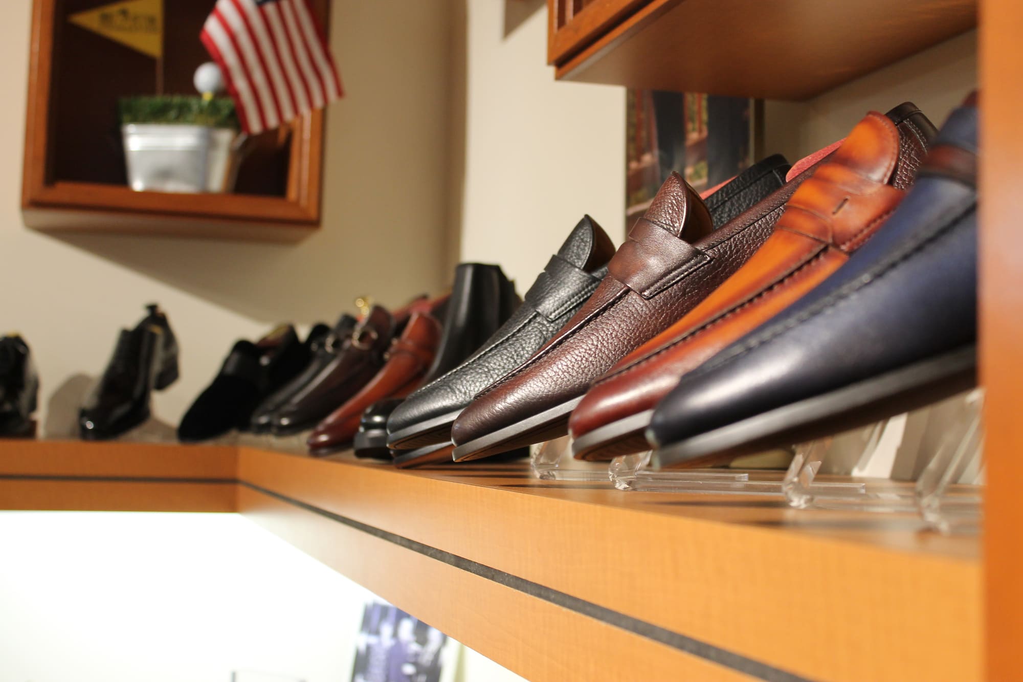 Leather penny loafers in black, brown, cognac and navy lined up on a lit shelf