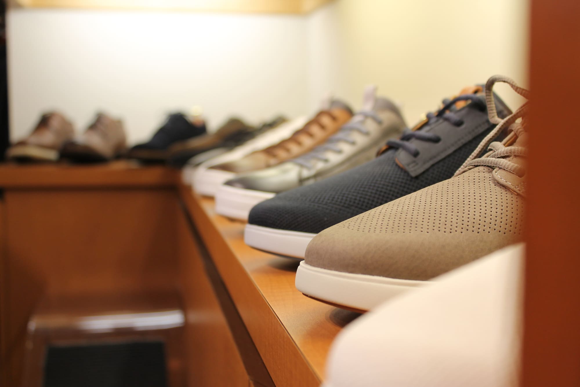 Perforated suede and knit sneakers in navy, taupe and grey on a wooden shelf